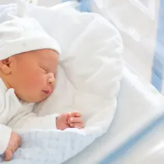 Śpiące noworodek w szpitalnym łóżeczku. Dowiedz się, jak wypełnić wniosek o becikowe, by zapewnić mu najlepszy start.