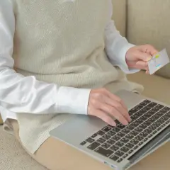Kobieta z kartą płatniczą na laptopie sprawdza, czy chwilówki są w BIK.