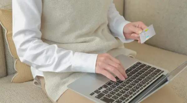 Kobieta z kartą płatniczą na laptopie sprawdza, czy chwilówki są w BIK.