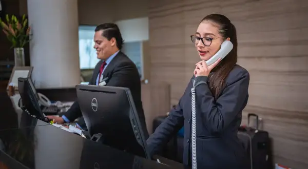 Recepcjonistka rozmawia przez telefon, podczas gdy jej kolega pracuje przy komputerze. Czy finloan dzwoni do pracodawcy?