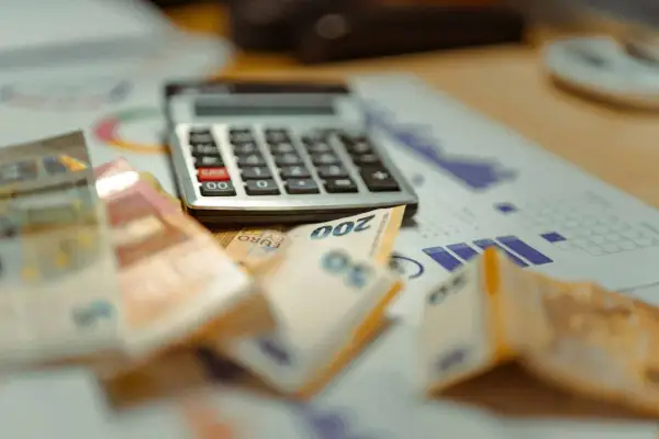 Kalkulator, banknoty euro i wykresy na biurku. Planujesz, jak usunąć zapytania w BIK?